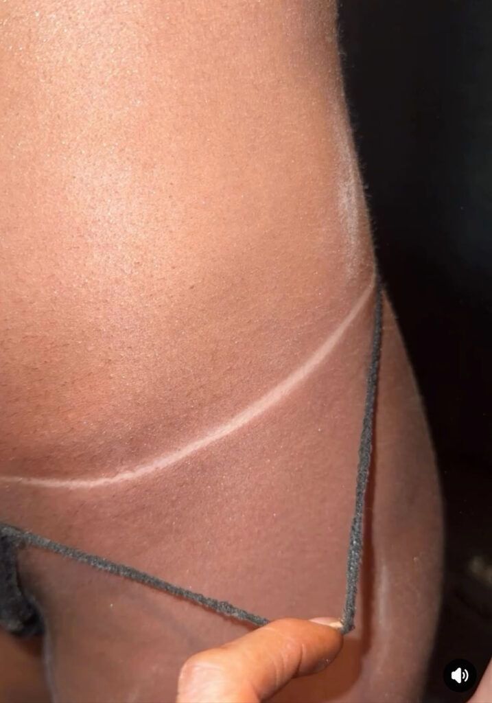 Close-up of a shoulder and hand holding a dark strap against skin and black fabric