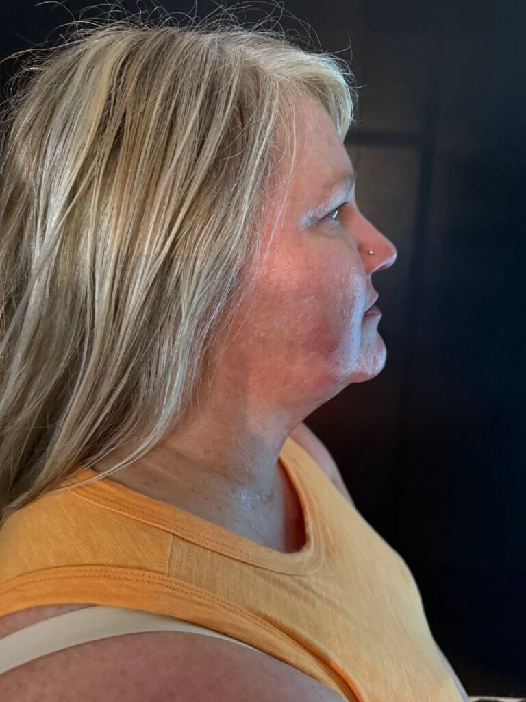 Profile view of a blonde woman in an orange shirt looking to the right indoors