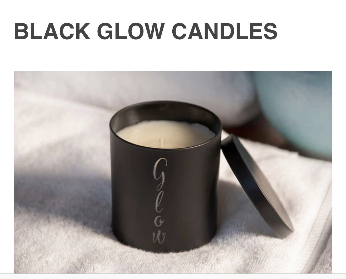 Black candle with lid beside it on a soft fabric background, labeled “Black Glow Candles”