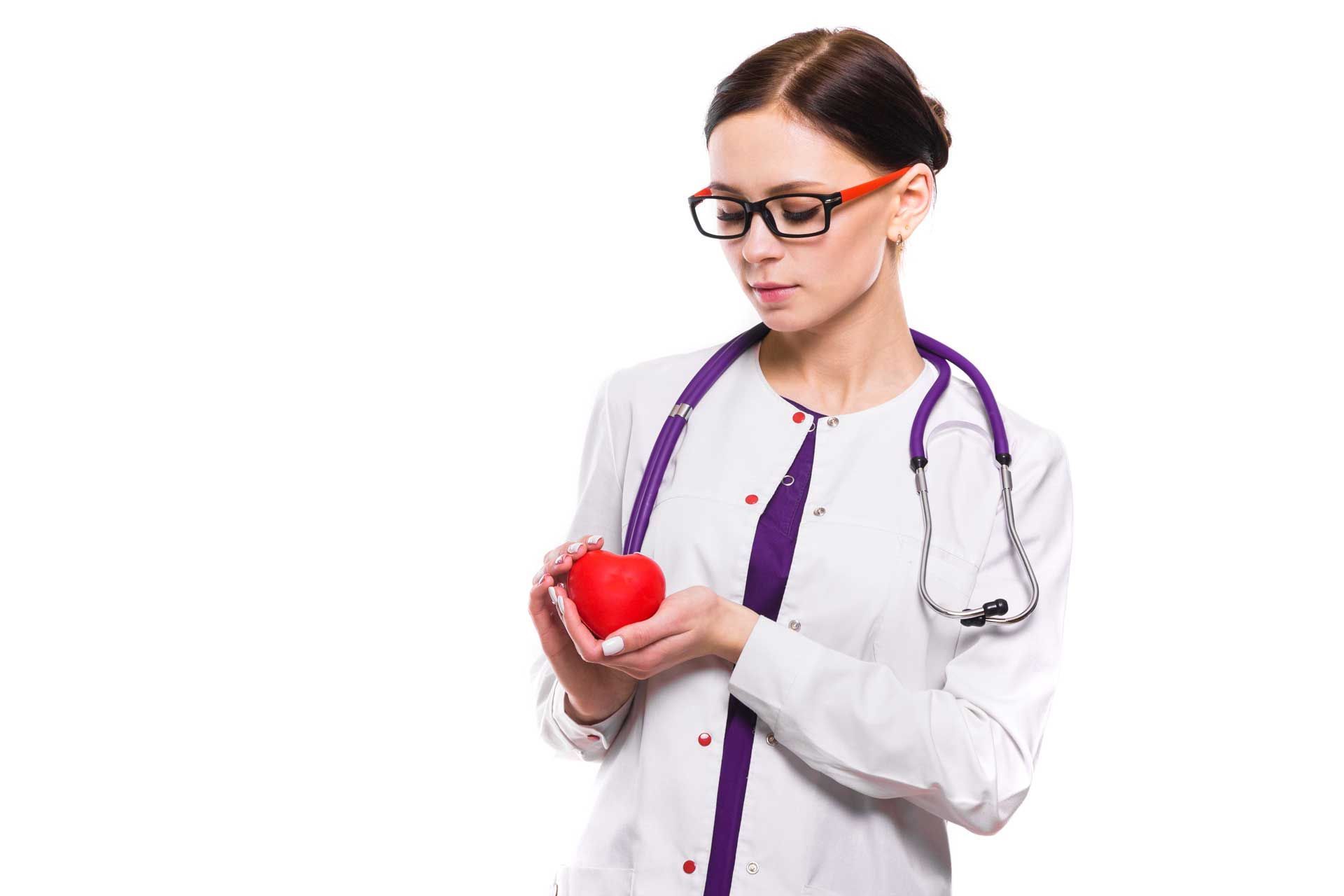 Doctor in white coat holding a red heart, wearing glasses and stethoscope.