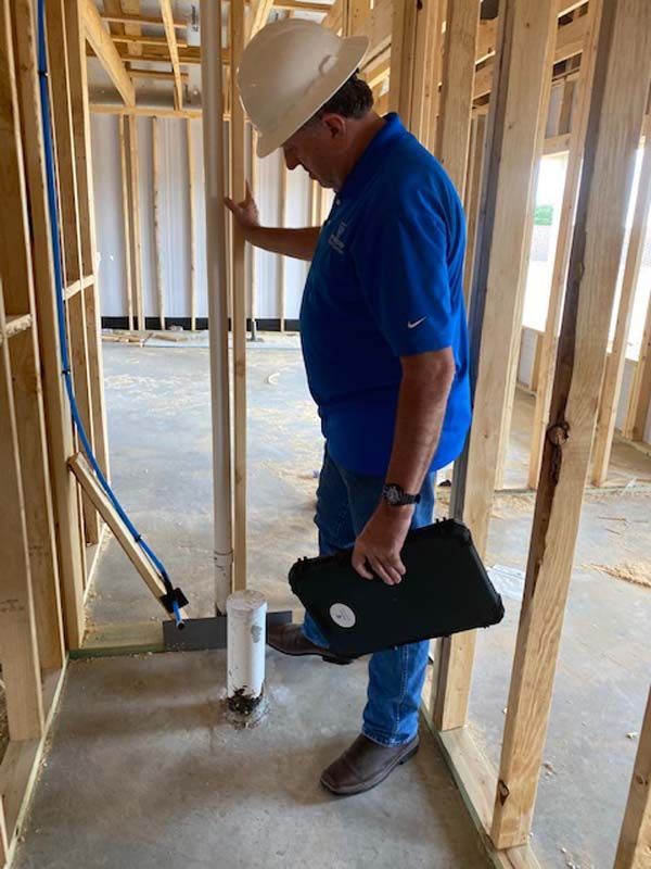 A man in a hard hat is looking at a pipe in a building under construction