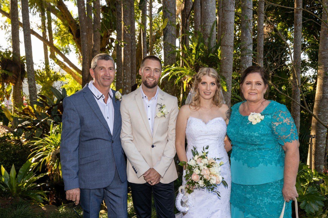 a bride and groom are posing for a picture with their parents .