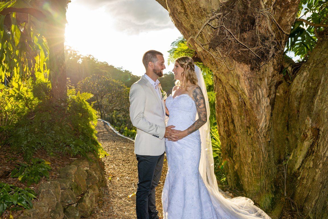 a bride and groom are posing for a picture under a tree .