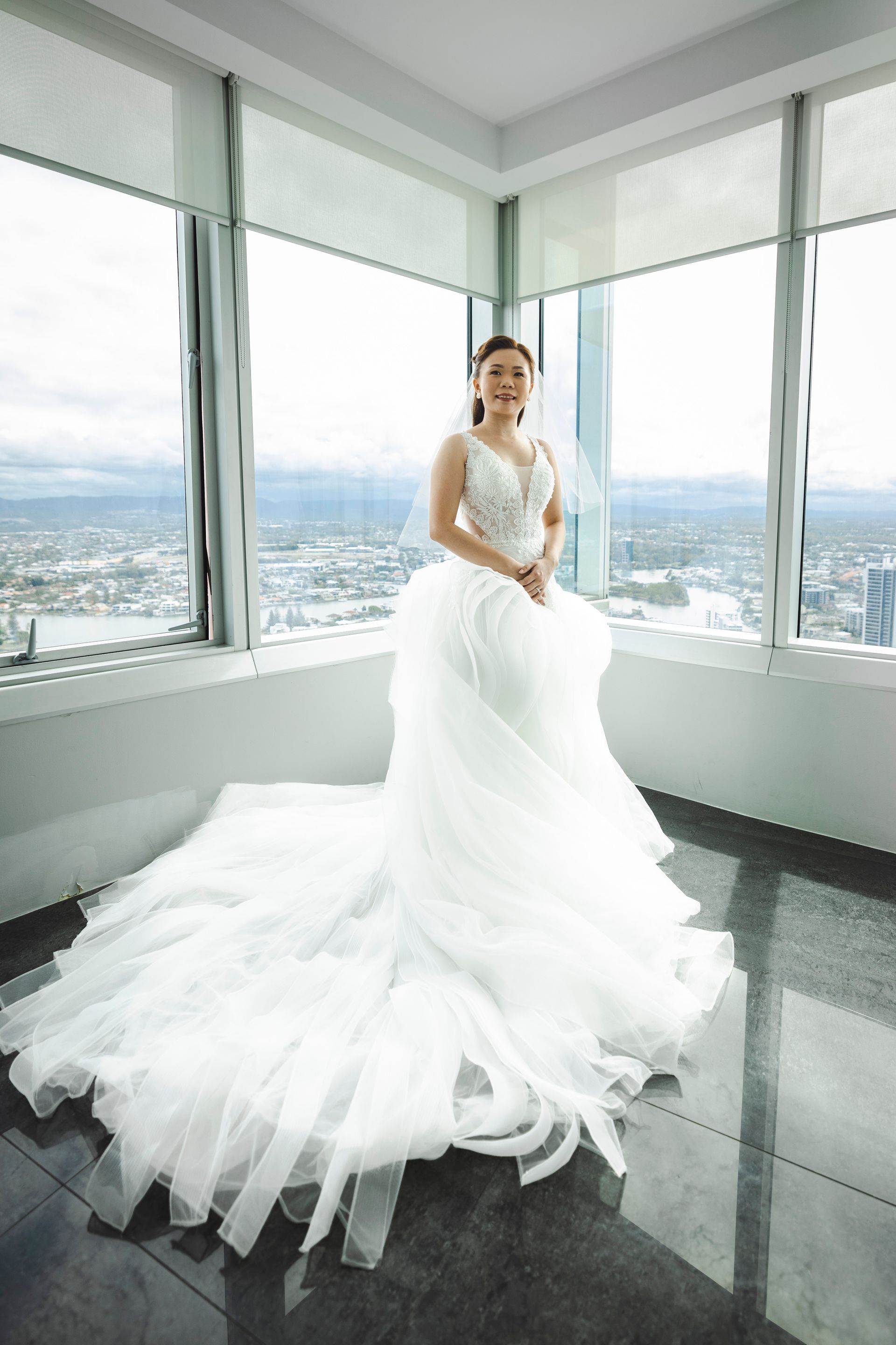 a woman in a wedding dress is standing in front of a window .