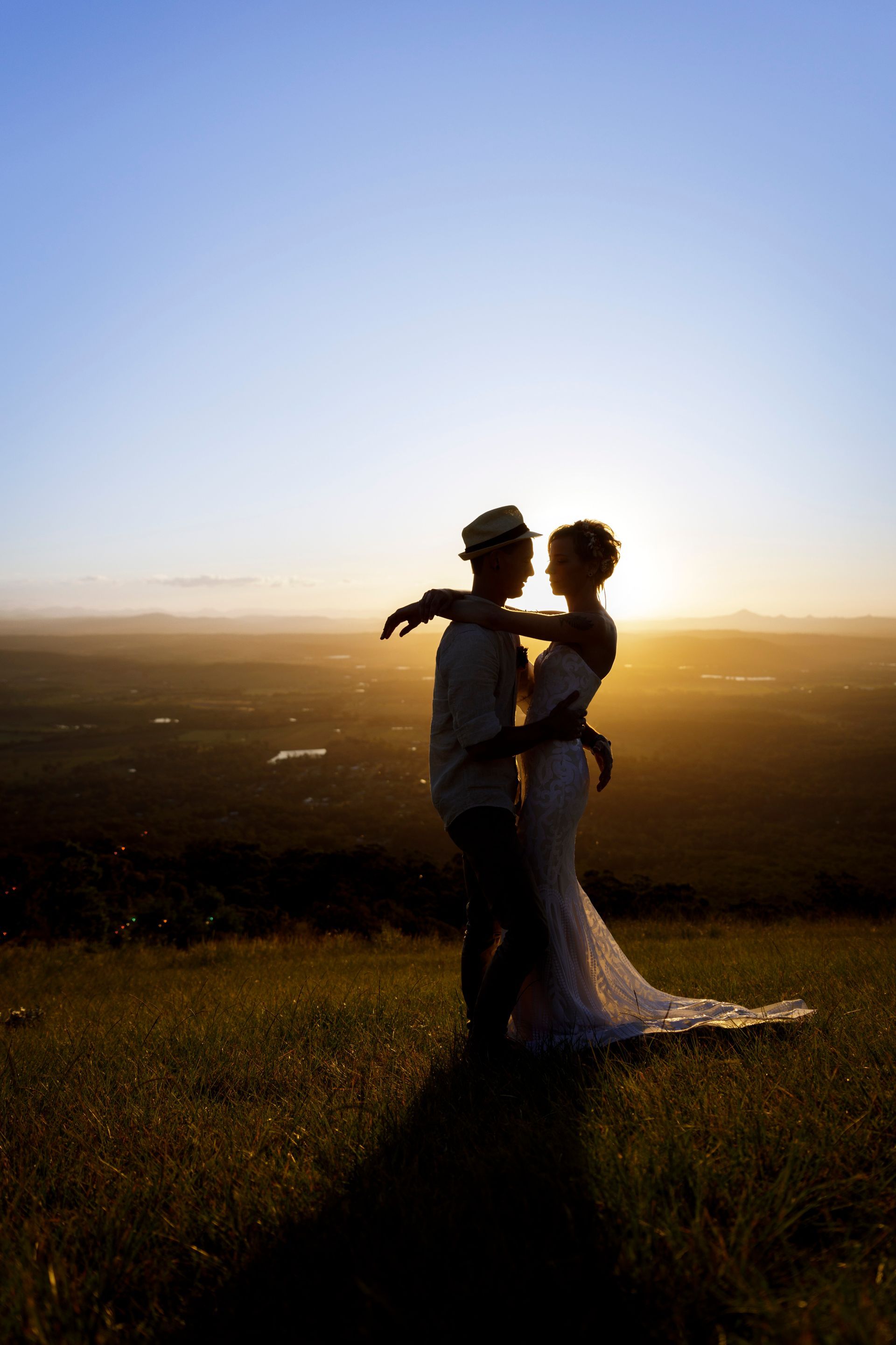 A bride and groom are dancing in a field at sunset on Tamborine Mtn