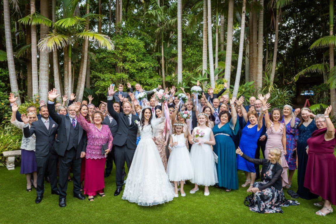 a large group of people are posing for a picture at a wedding .