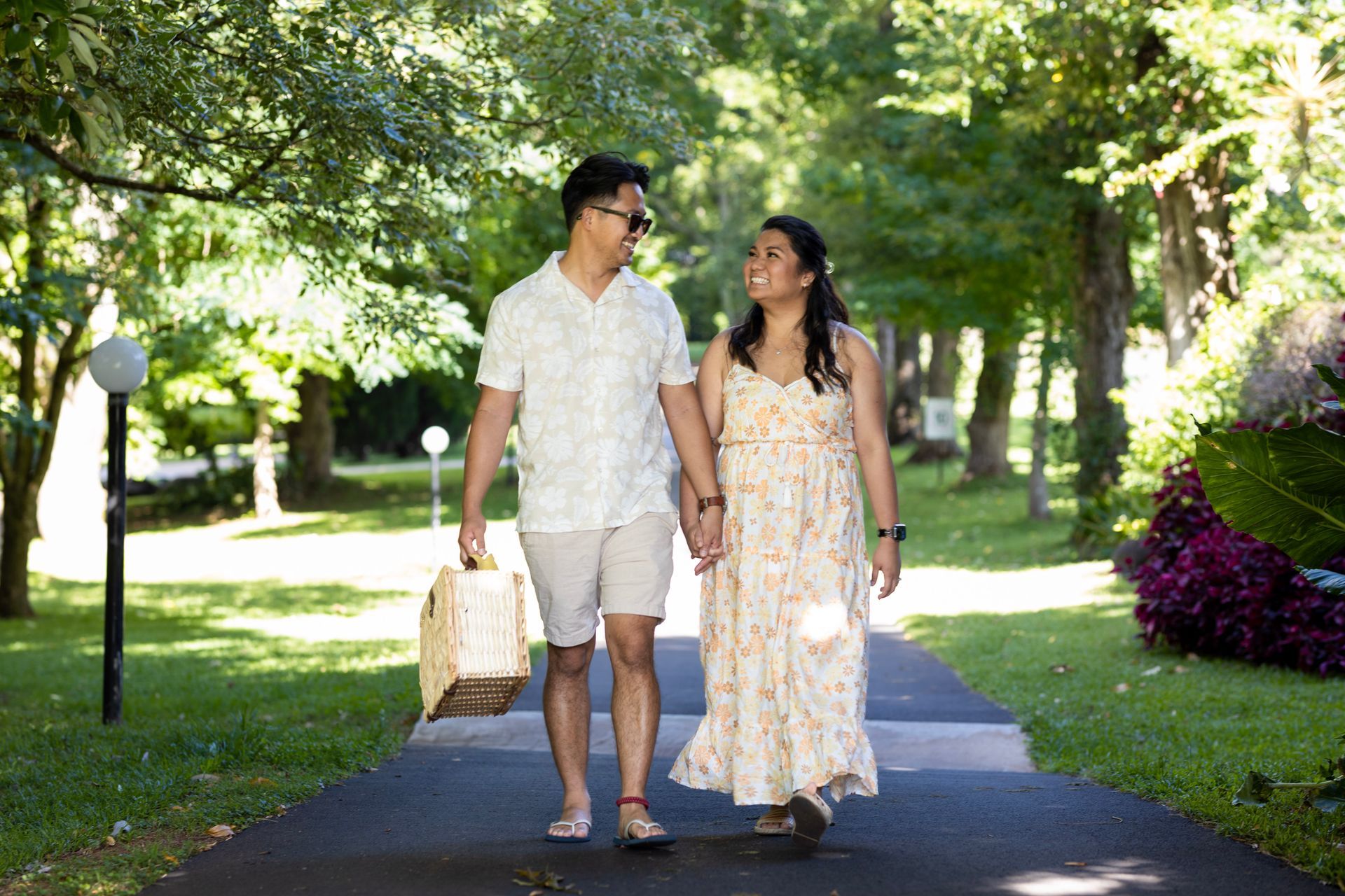a man and a woman are walking down a path holding hands .
