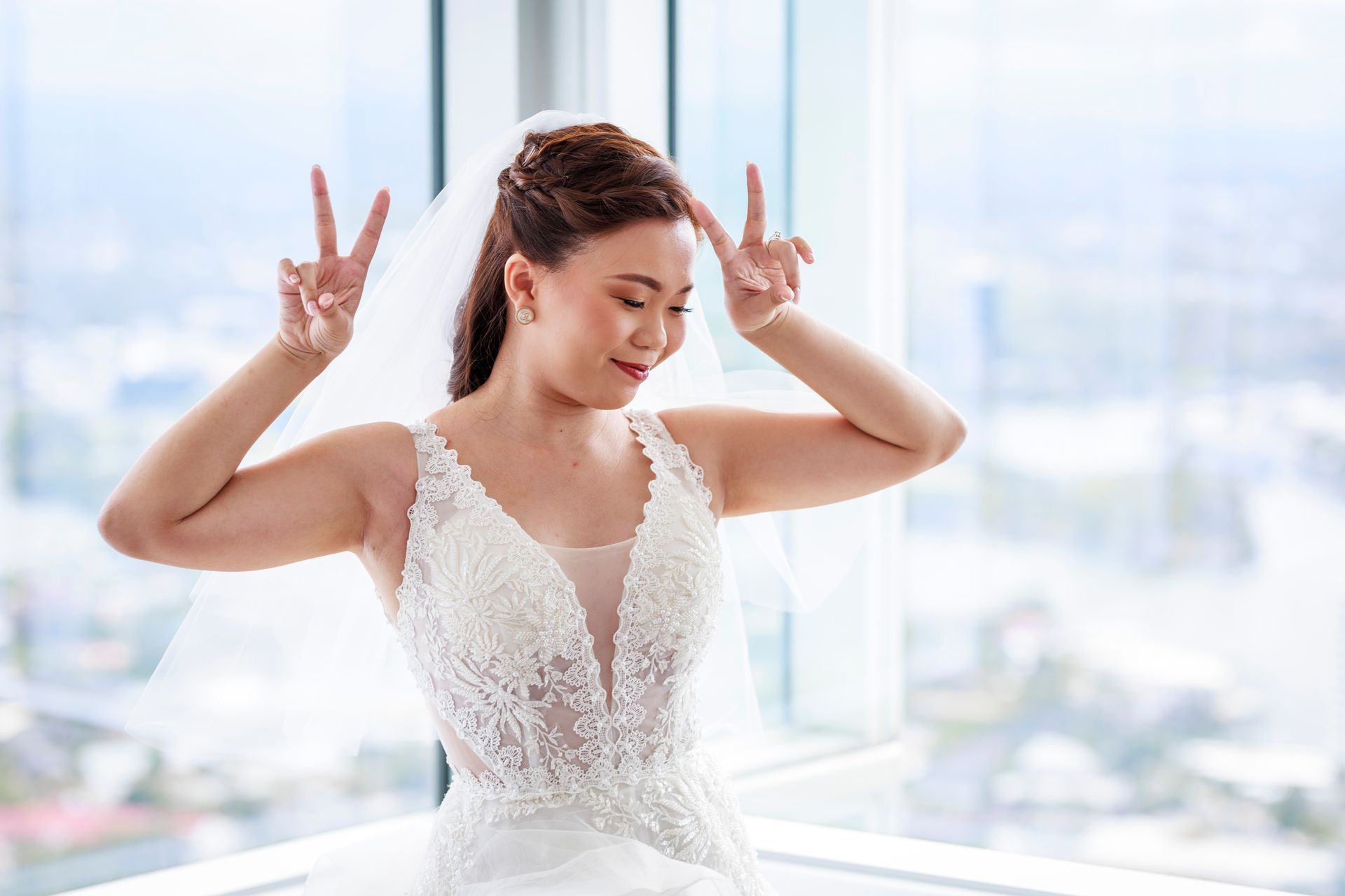 a bride in a wedding dress and veil is giving a peace sign .