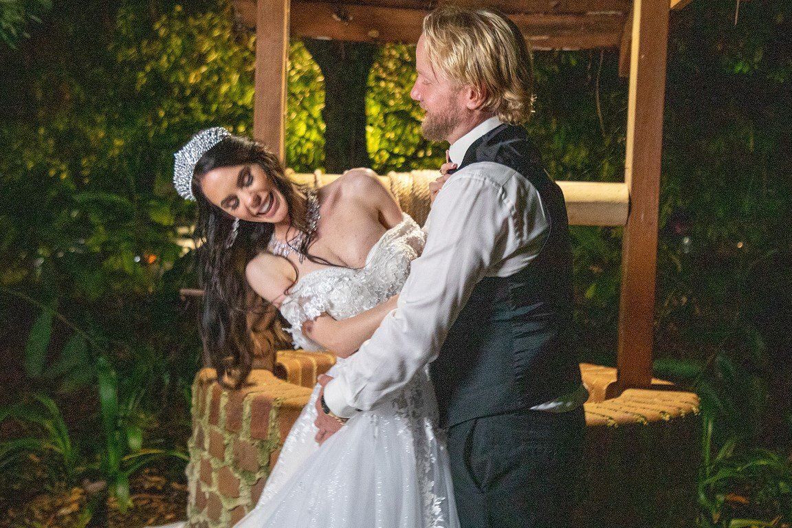 a bride and groom are posing for a picture in front of a gazebo .