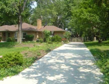 A concrete driveway leading to a house surrounded by trees.