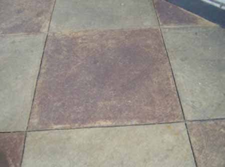 A close up of a tiled floor with a purple stain on it.