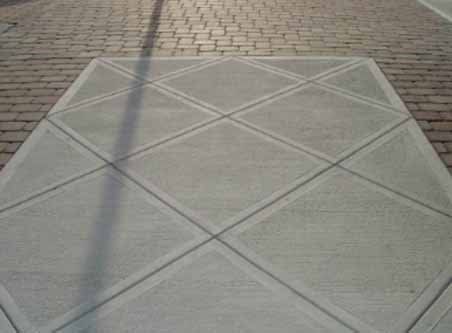 A brick sidewalk with a concrete walkway in the middle of it.