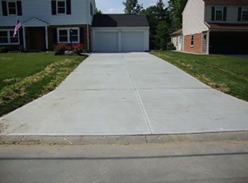 A concrete driveway leading to a house with two garage doors