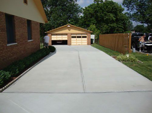 A brick house with a concrete driveway leading to it