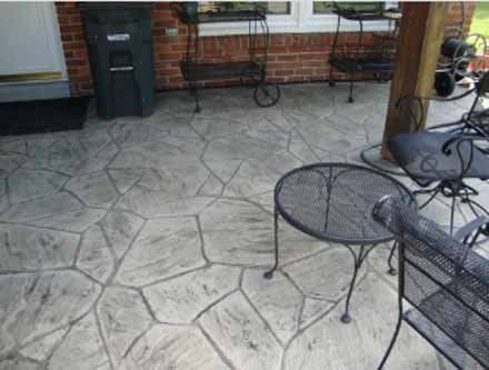 A patio with a table and chairs and a trash can.