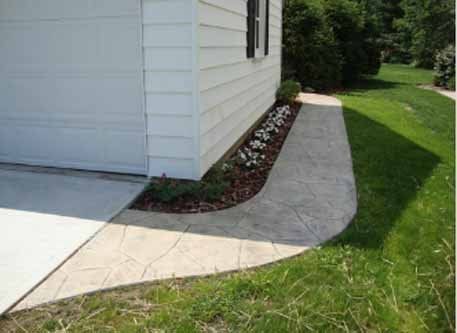 A sidewalk leading to a garage next to a house.