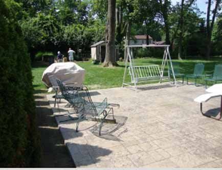 A patio with chairs , a swing and a grill