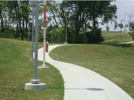 A concrete walkway going through a grassy field