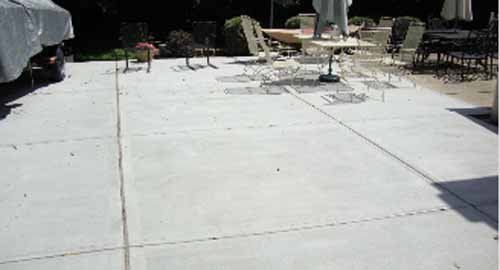 A concrete patio with a table and chairs on it.