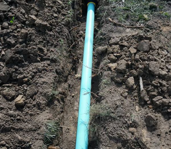 A blue pipe is sitting in the middle of a dirt field.