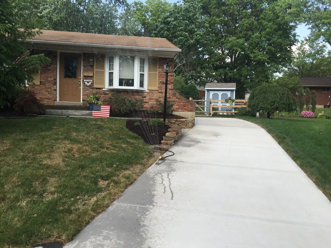 A brick house with a concrete driveway leading to it.