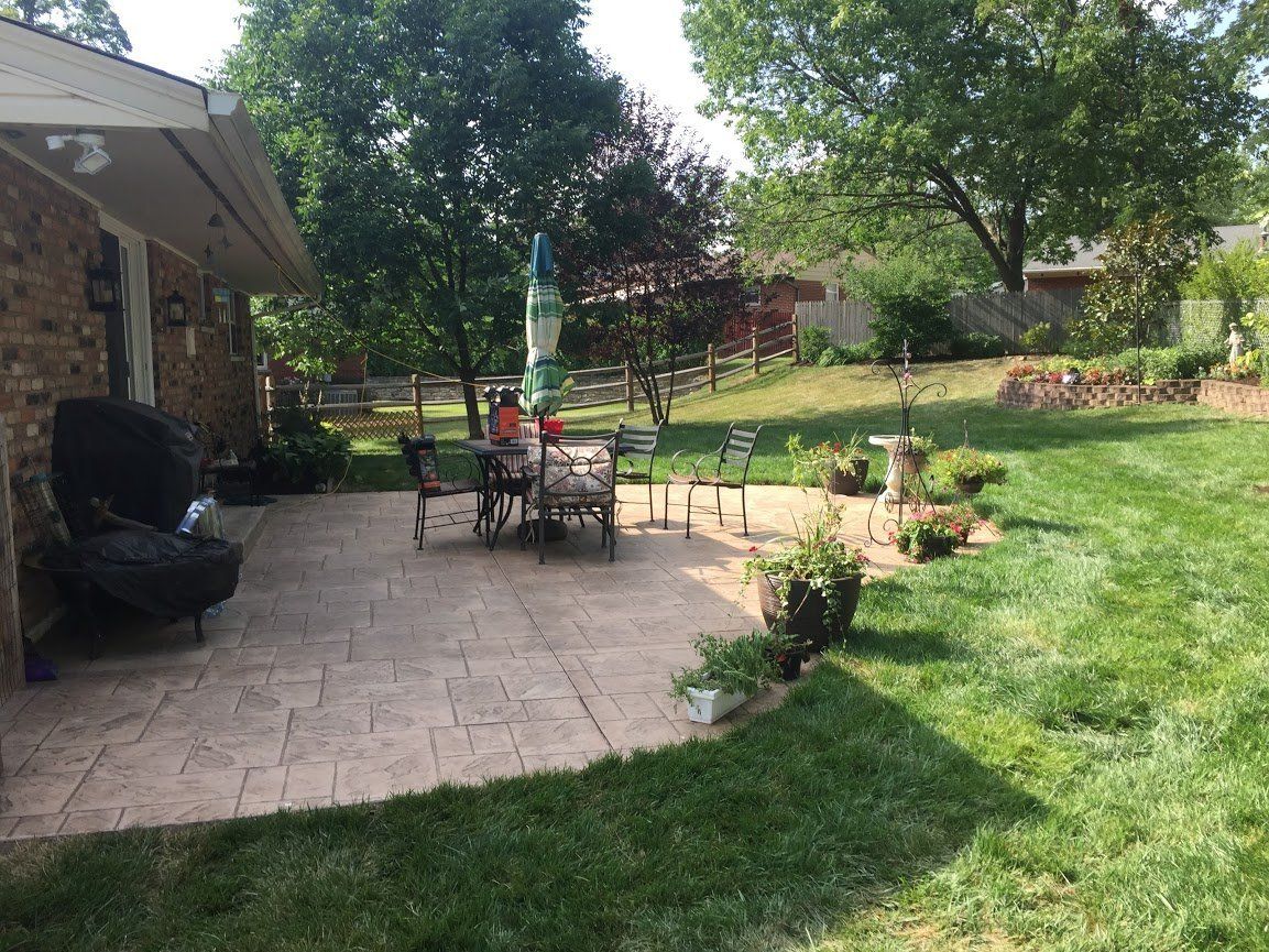 A patio with a table and chairs in the backyard of a house.