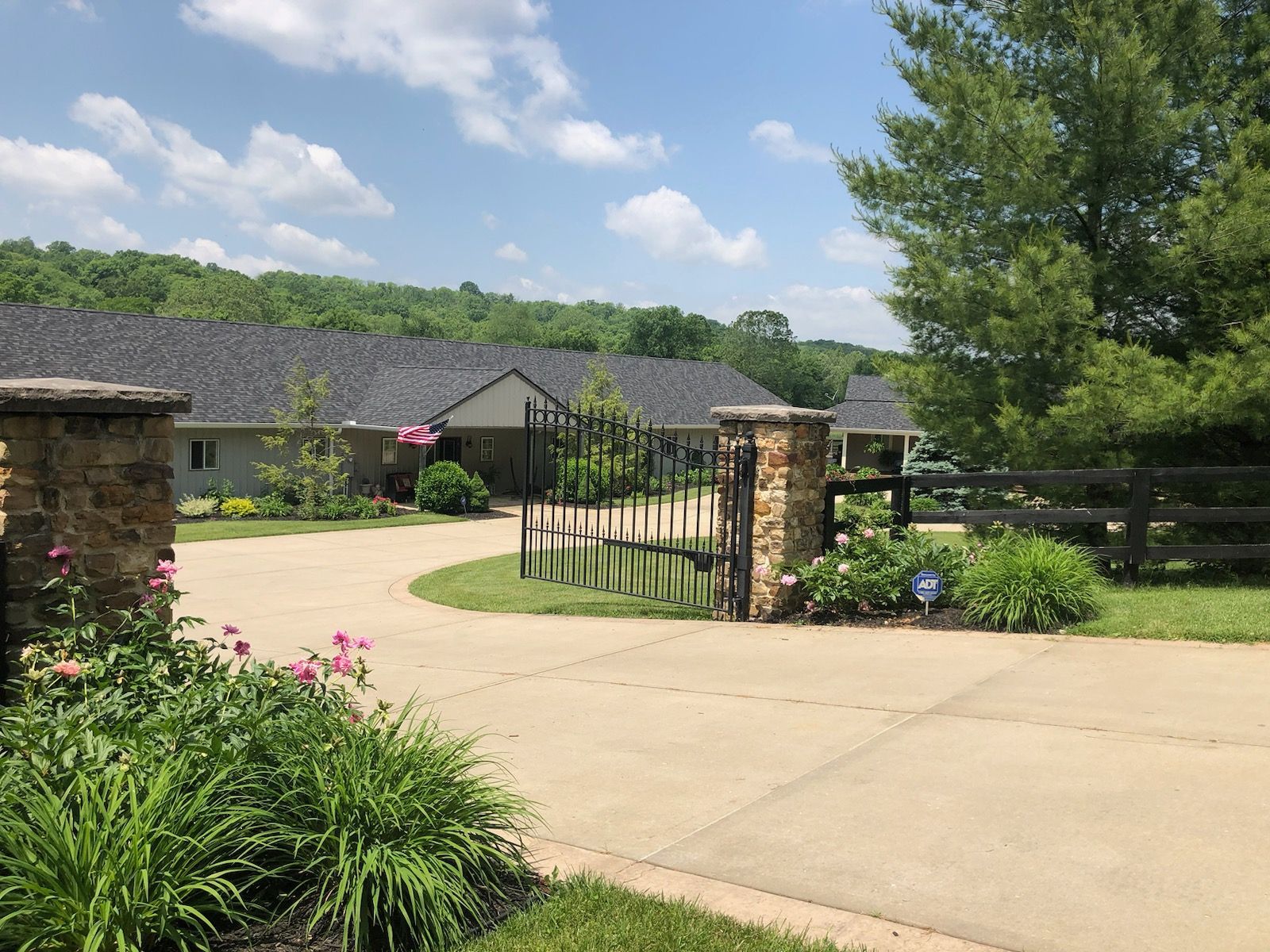 A driveway leading to a house with a fence and a gate