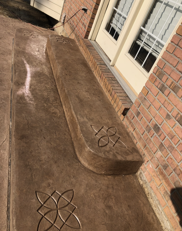 A concrete walkway with a celtic design on it in front of a brick building.