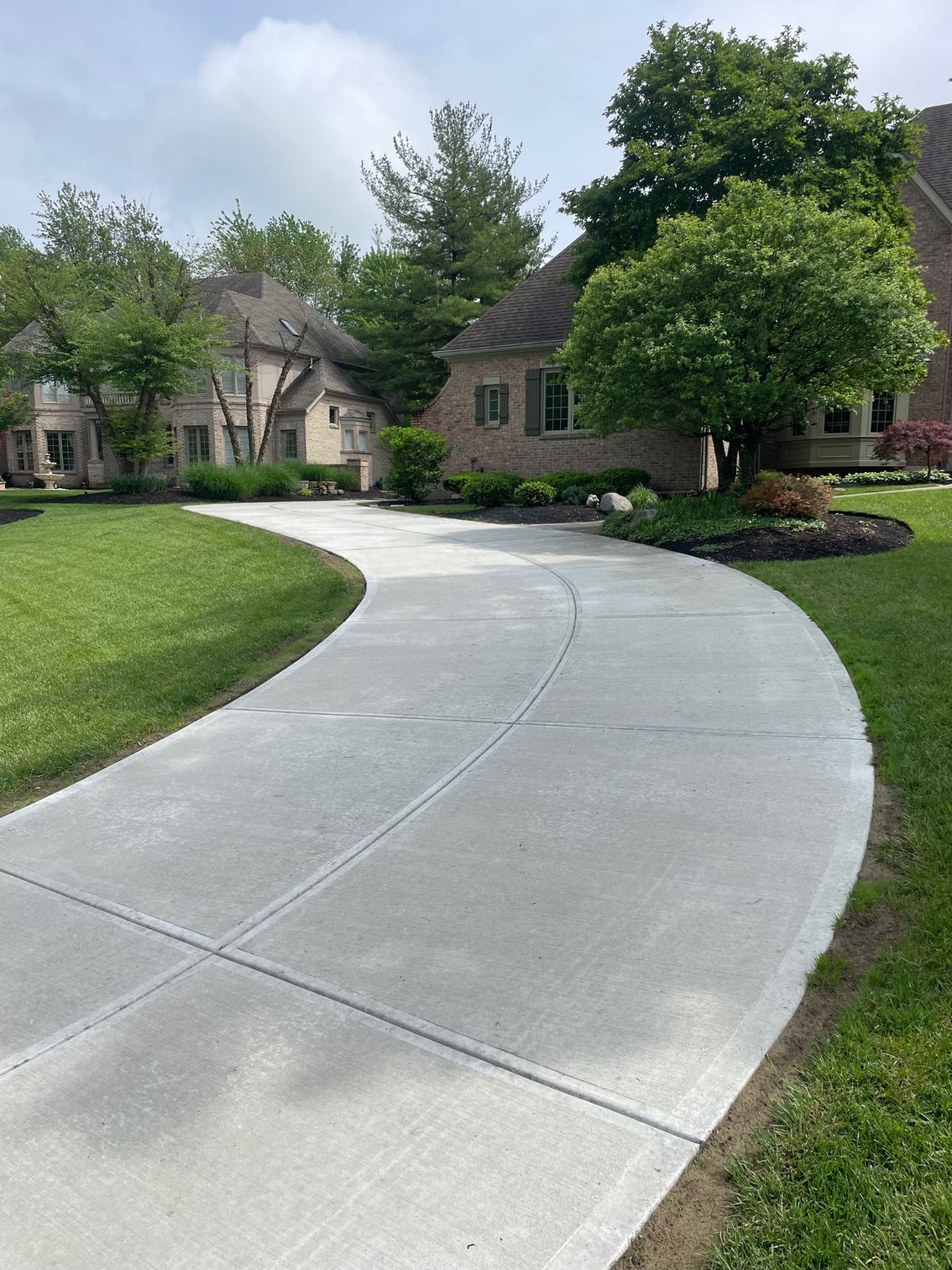 A curved concrete driveway leading to a large house.