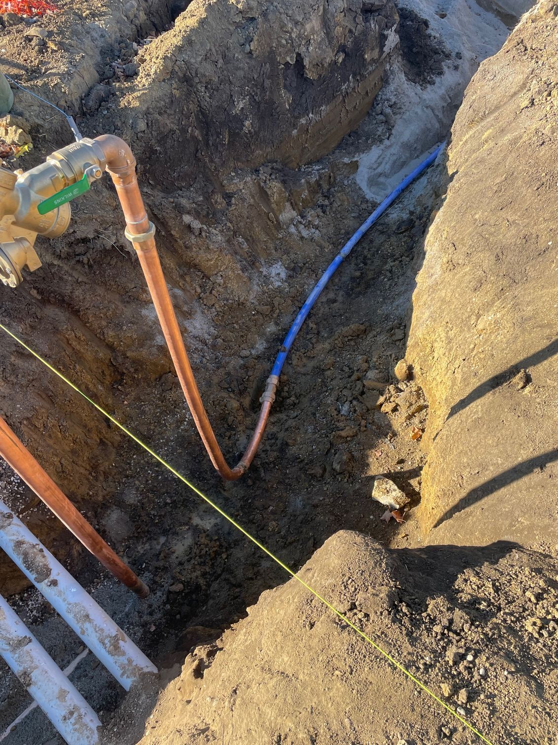 A copper pipe is being installed in a hole in the ground.