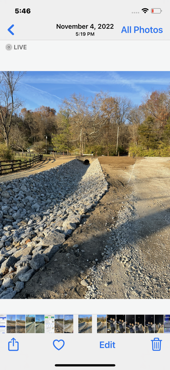 A phone screen shows a picture of a rock wall being built.