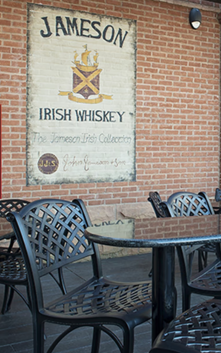 A sign for jameson irish whiskey hangs on a brick wall
