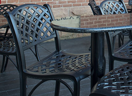 A row of black chairs and tables with a brick wall in the background