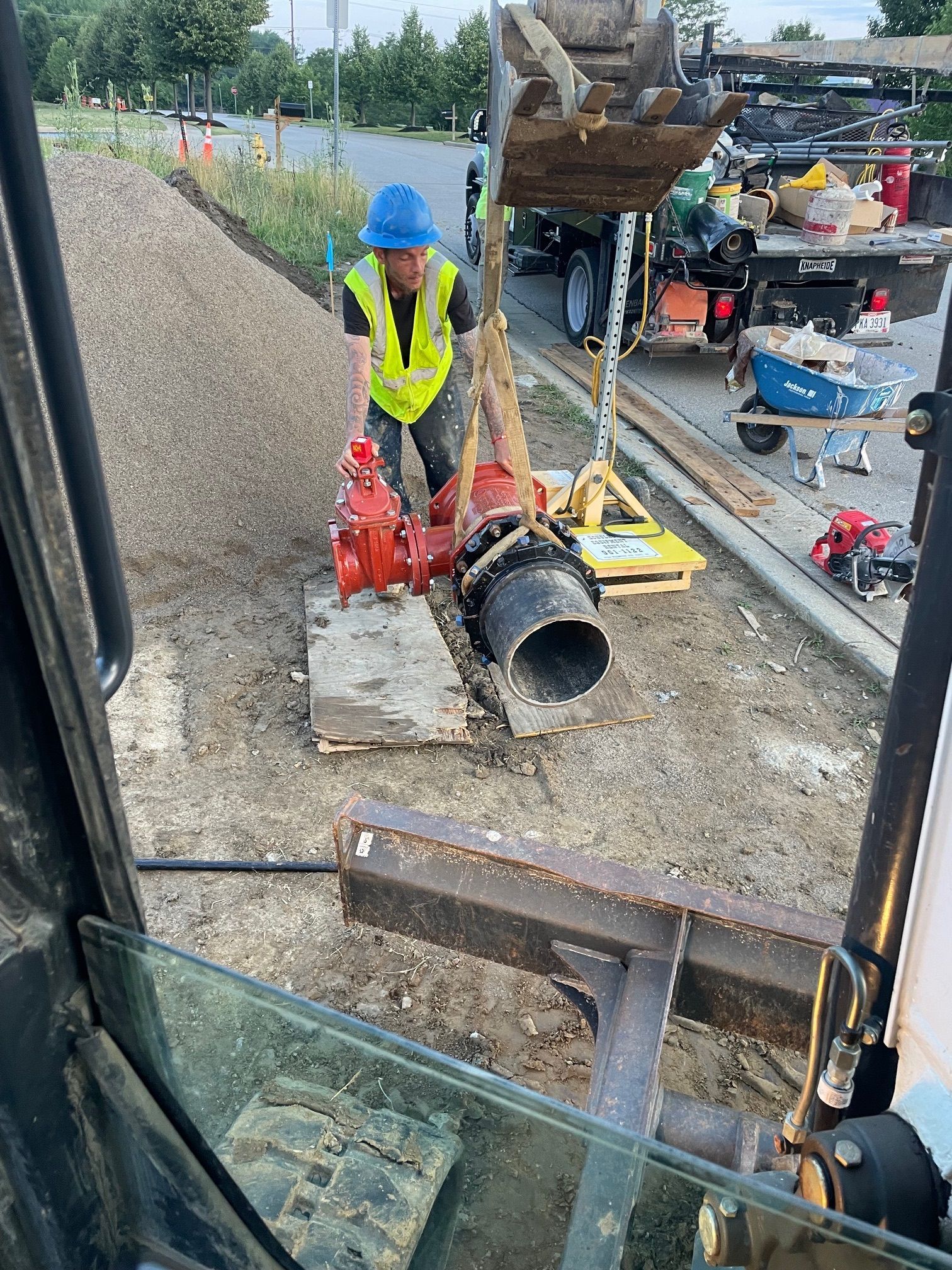 A construction worker is working on a pipe in the dirt.