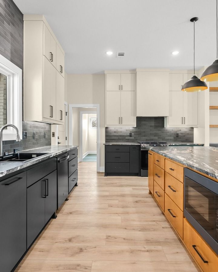 Modern kitchen with black and wood cabinets, light countertops, and a windowed sink area