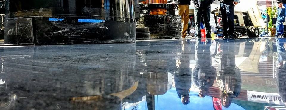People walking through a rain-slicked city street, reflected in the wet pavement.