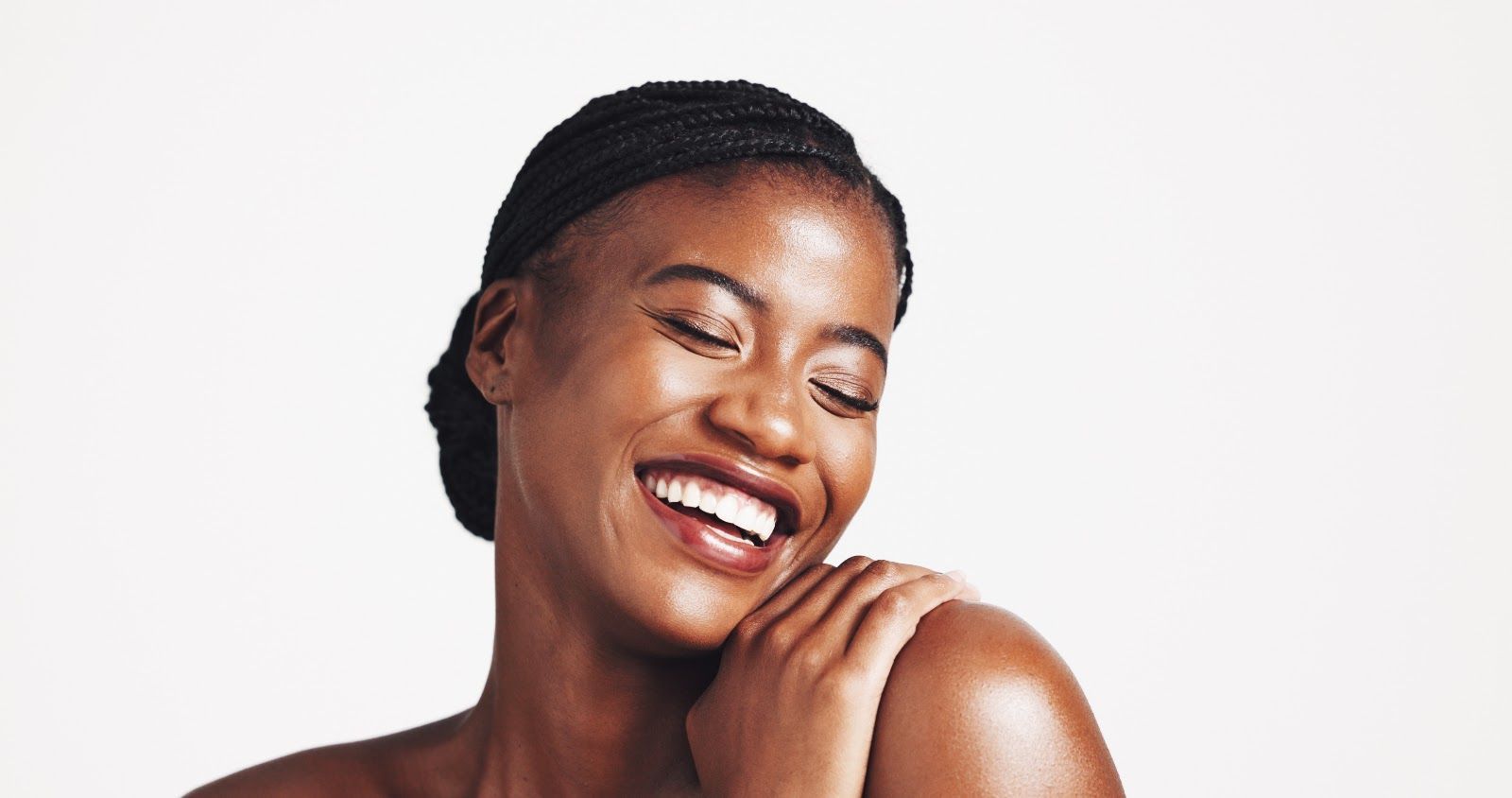 Smiling person with eyes closed, resting chin on hand against a white background