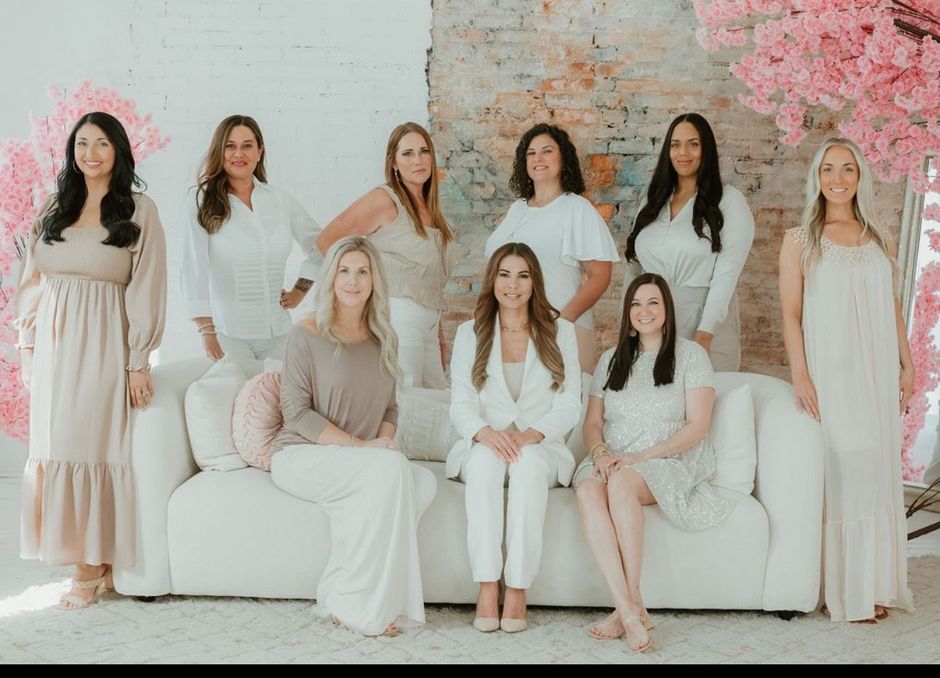 A group of women are posing for a picture while sitting on a couch.