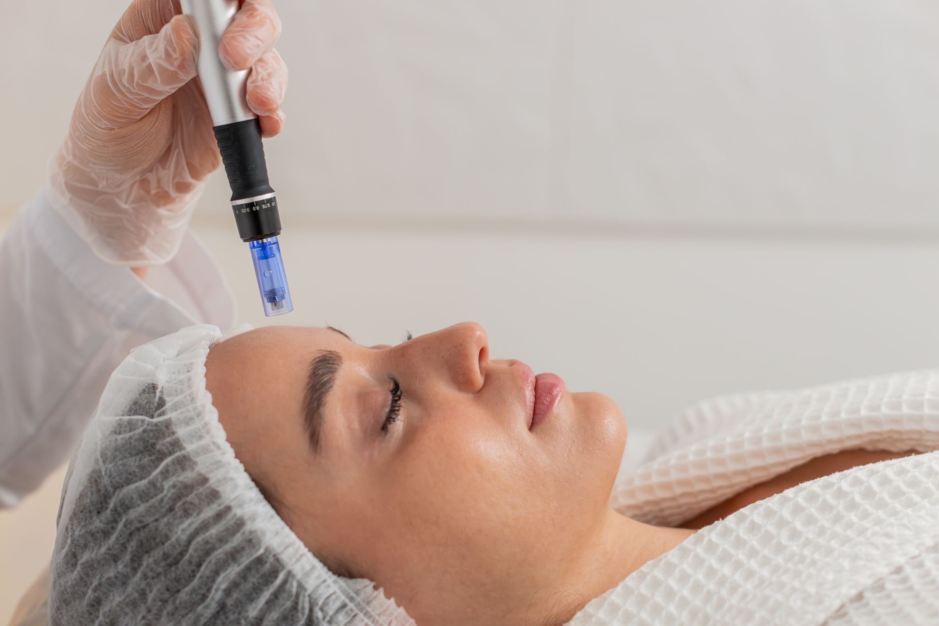 Cosmetic treatment with a handheld device near a woman’s face as she lies on a treatment bed