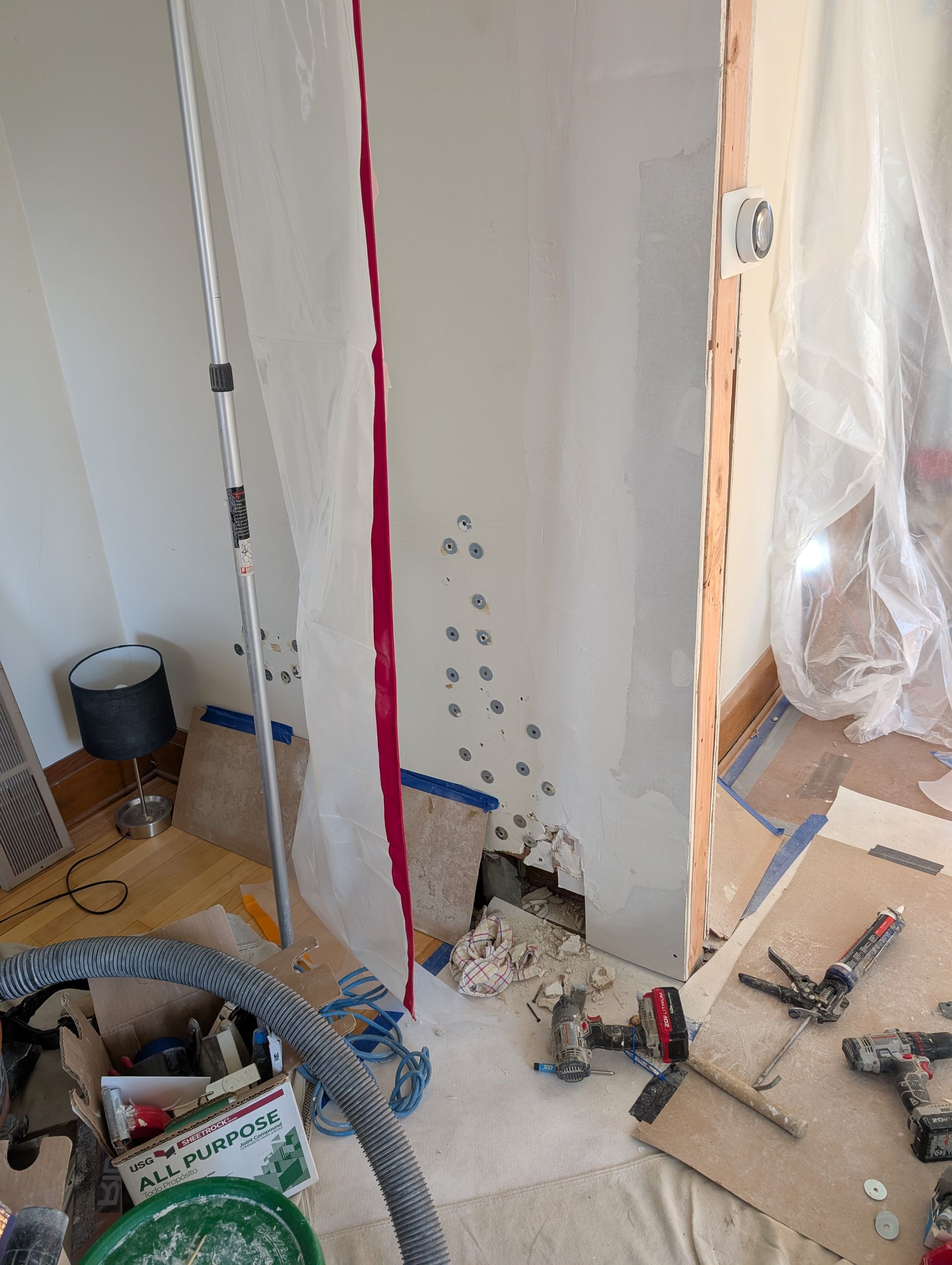 Plaster wall repair showing a glue and clamp system used to secure loose plaster to wood lath before finishing with Durabond compound.