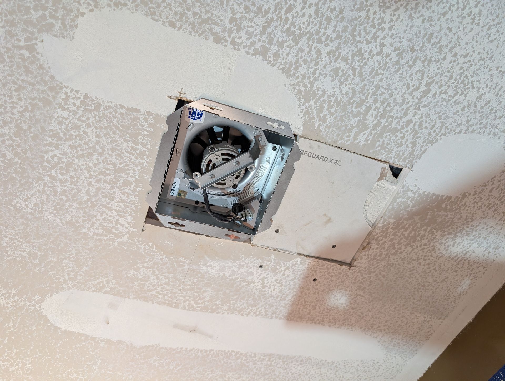 Bathroom ceiling renovation with a smaller, quieter exhaust fan, drywall patching around the new fixture, and popcorn ceiling texture removal.