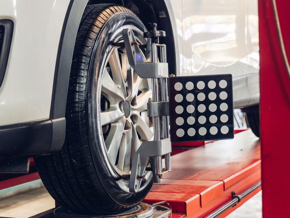 Car wheel with alignment equipment on a red lift.