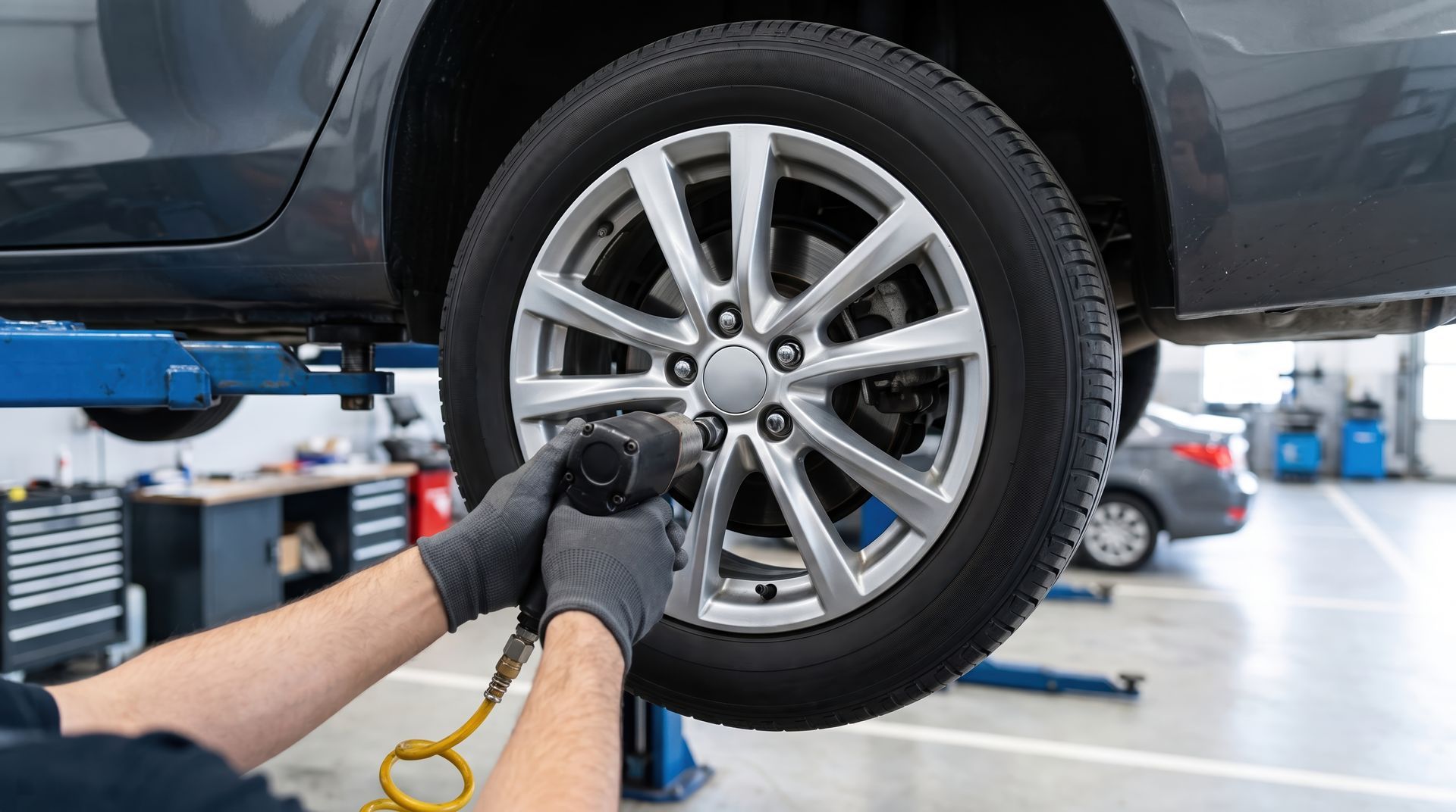 Mechanic using a wrench to remove a car wheel in an auto repair shop
