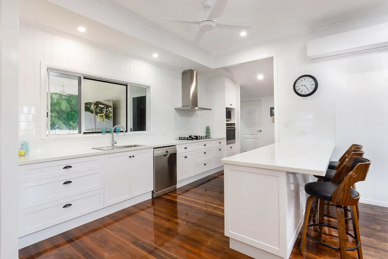 A Kitchen with White Cabinets and Hardwood Floors and A Clock on The Wall — JWB Joinery in Aitkenvale, QLD