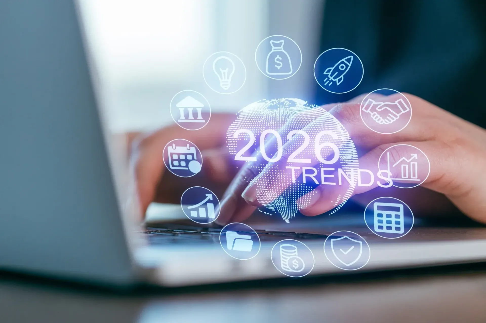 Des mains tapent sur un ordinateur portable avec une superposition numérique affichant un globe terrestre, « TENDANCES 2026 » et diverses icônes d'entreprises.