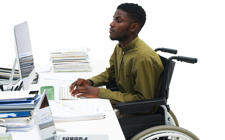Un homme en fauteuil roulant est assis à un bureau en utilisant un ordinateur.