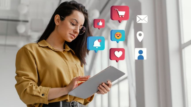 Dans un bureau lumineux, une personne concentrée utilise une tablette, entourée d'icônes flottantes de réseaux sociaux et de commerce électronique.