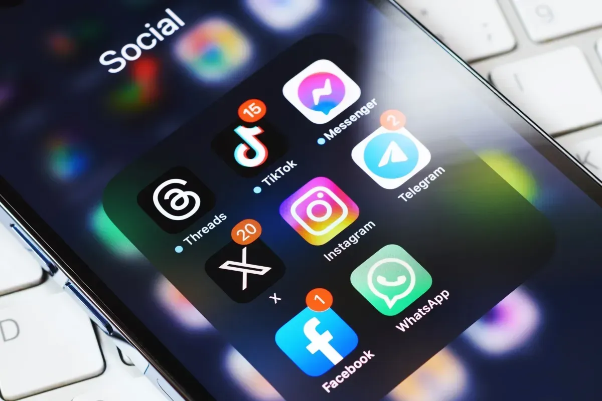 Gros plan sur l'écran d'un smartphone montrant un dossier « Réseaux sociaux » contenant des icônes pour TikTok, Messenger, Telegram et autres.