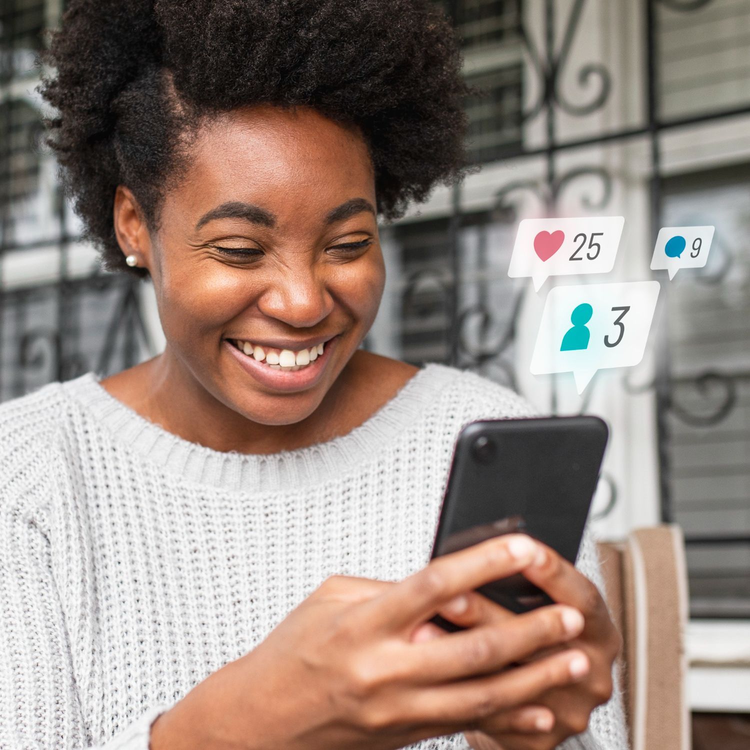 Une femme sourit en regardant son téléphone portable.