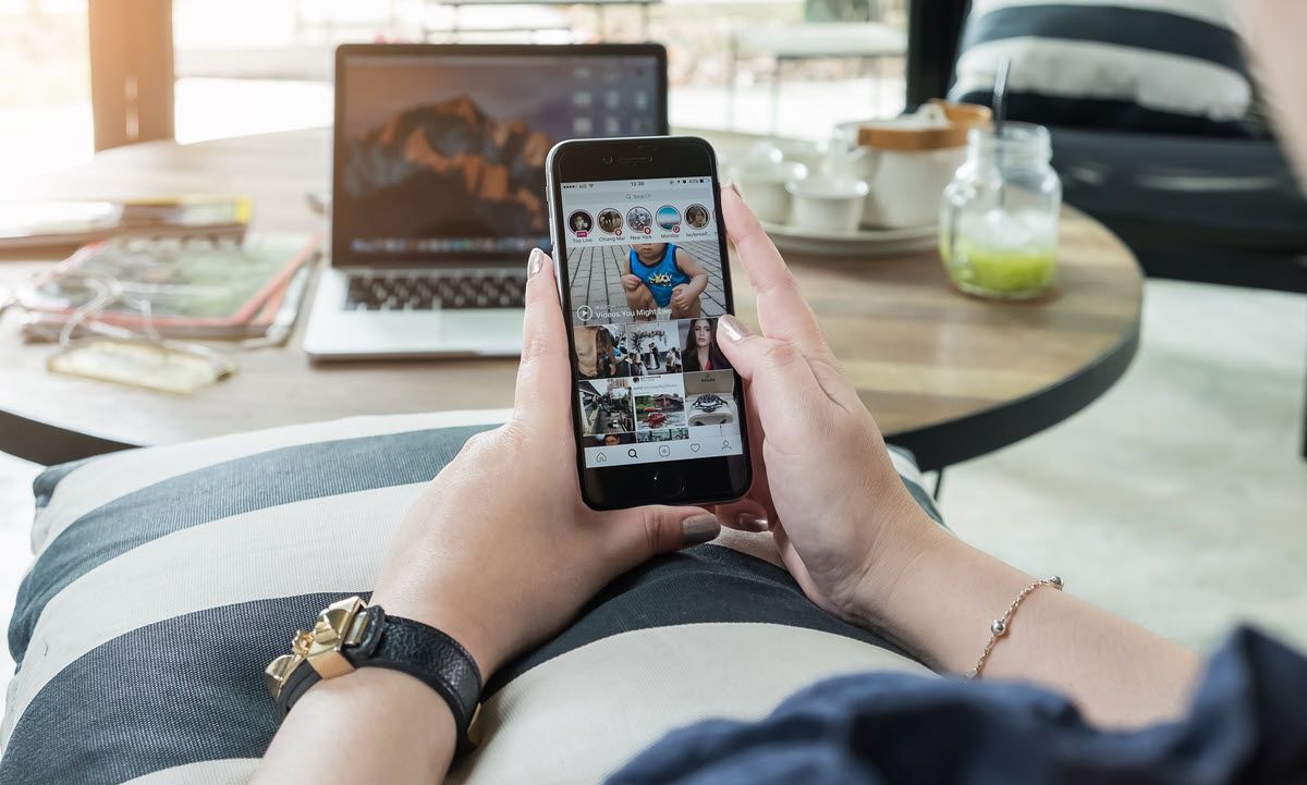 Une femme est assise sur un canapé tenant un téléphone portable dans ses mains.